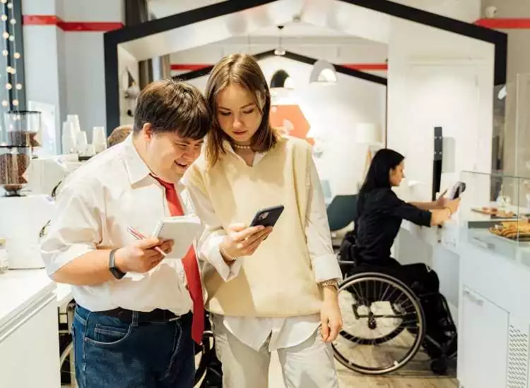 A girl sharing her phone to a male person with a down syndrome